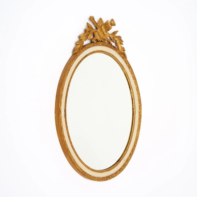 Oval mirror from France featuring a hand-carved frame. The frame, made of wood, supports a central oval mirror original to...