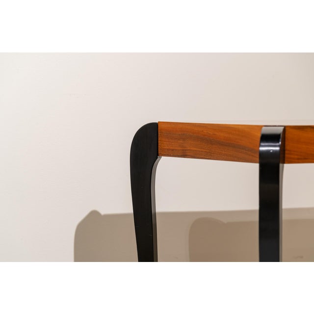 Art Deco style side table in walnut and ebonized wood. The tabletop is rectangular and features a thinner lower shelf that...