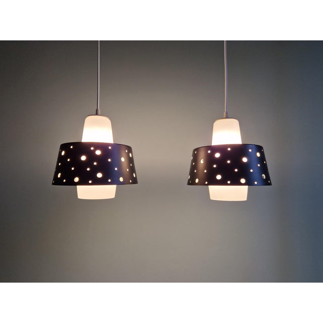 Duo of Scandinavian pendant lights in white opaline and openwork black lacquered metal, 1960s. Each of the pendant lights...