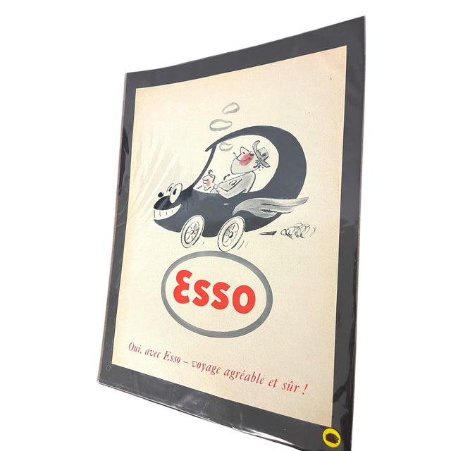French advertising print for Esso, featuring a whimsical cartoon illustration of a smiling motorist driving a car with a...