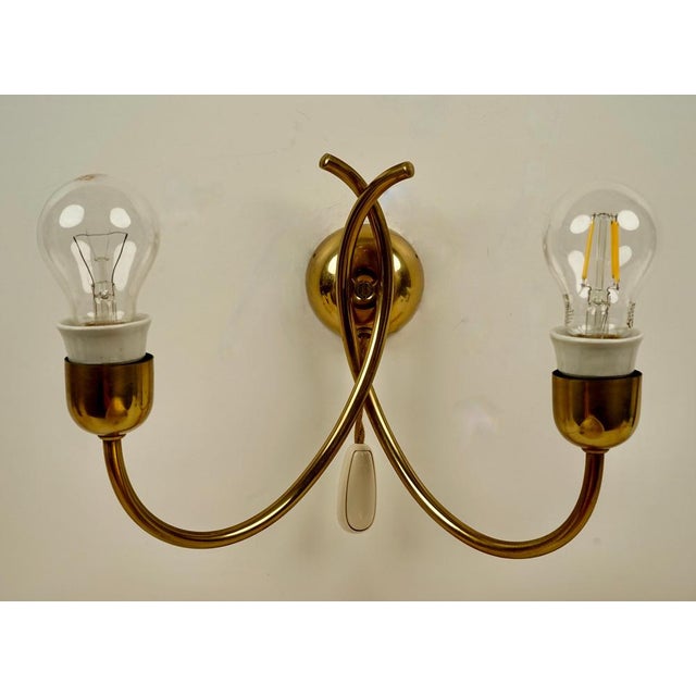 A beautifully made wall lamp designed by josef frank and made in austria in the 1950's. The lyrically shaped brass tubing...