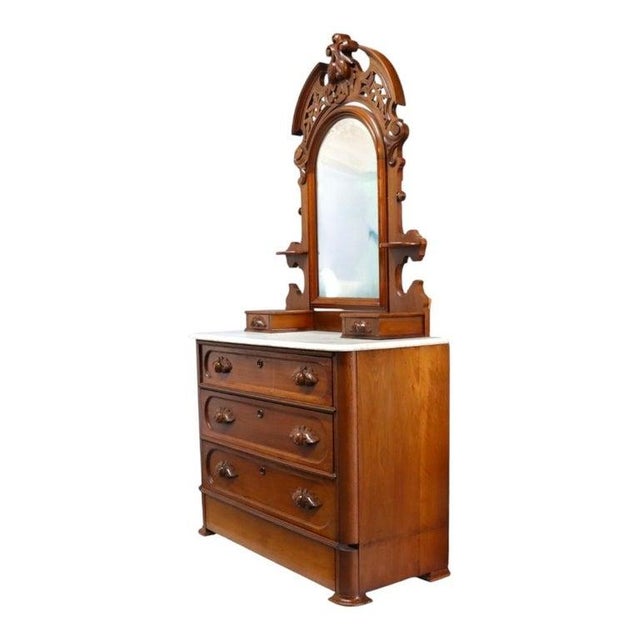This antique dresser, circa 1880, features a finely carved walnut construction and a polished marble top. The dresser is...