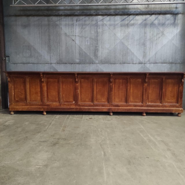 This long wooden counter (396 cm long) is a beautiful vintage piece with rich patina and an elegant carved front. On the...
