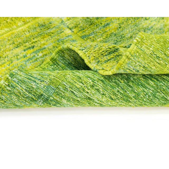 This striking hand-knotted wool rug commands attention with its vivid lime green and neon yellow palette. Its bold, high-...