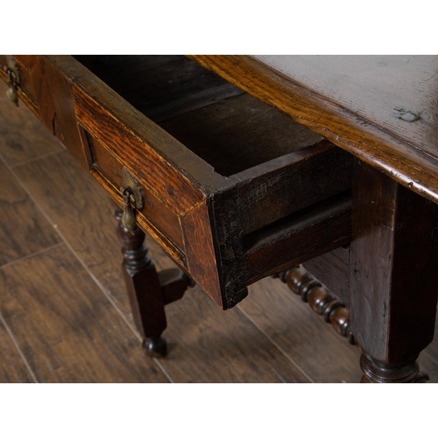 An English carved geometric front oak side table from the 19th century, with single drawer, bobbin legs, H-form cross...