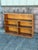 A vintage pine bookcase featuring a warm, naturally aged finish, exposed wood grain, and a simple architectural silhouette.