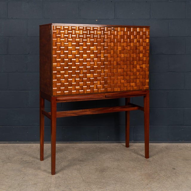 A striking italian dry bar cabinet dating from the 1960s, raised on a refined, slender stand. The front features an...