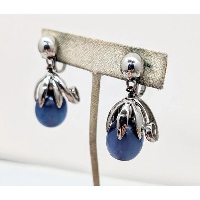 1950s silvertone round domed top with blue moonglow resin drop with curled top "cumquat" clip earrings. Marked "NAPIER" in...