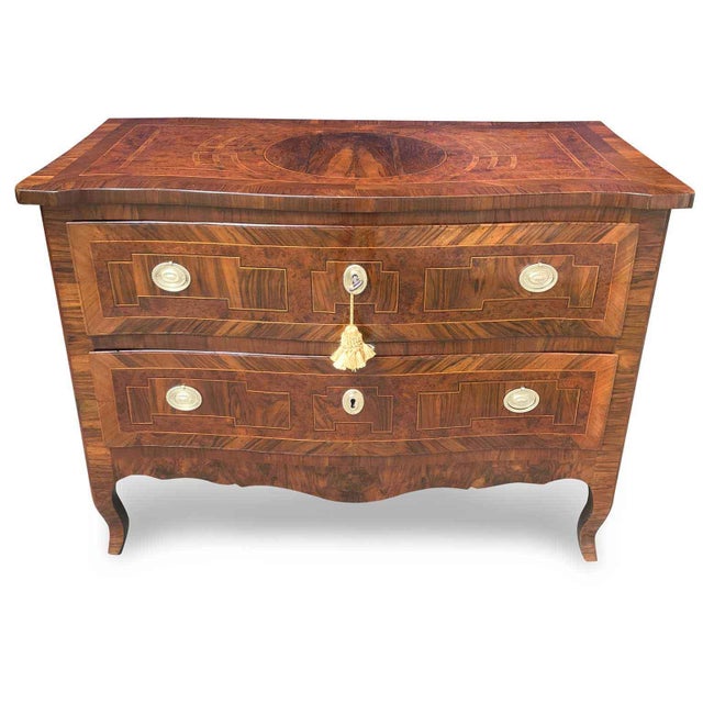 An 18th-century Emilian chest of drawers, with two gently contoured drawers and entirely veneered in walnut, walnut burl,...