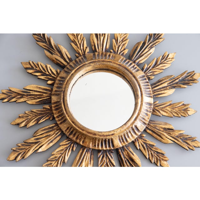 A stunning Mid-Century French giltwood sunburst or starburst mirror with lovely gilt patina and finely carved rays. It...