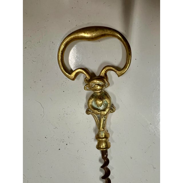 Early 1900s Solid Brass cork screw bottle opener. The handle has a monkey. Measuring 6” long.