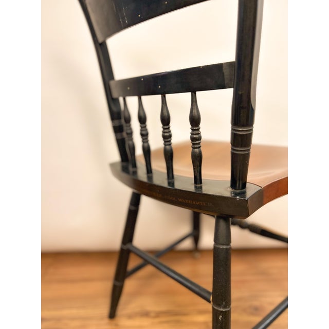 Classic Hitchcock chair featuring a deep black finish with traditional gold stenciled detailing and turned spindle back....