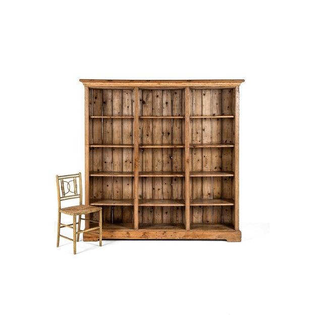 A large open pitch pine bookcase with an arrangement of fifteen individual partitions over four shelves. A gently...