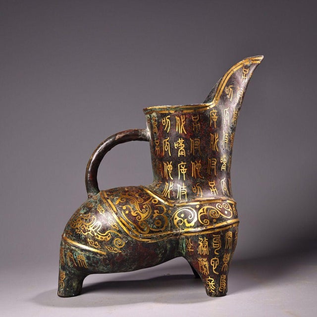 This is a cast bronze tripod vessel featuring extensive gold inlay (gilt bronze) decoration. The piece has a distinctive...