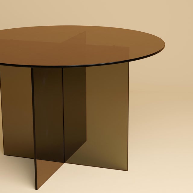 The Sado is a bronzed glass dining table, a study in transparency built from Italian glass rather than stone. It trades...