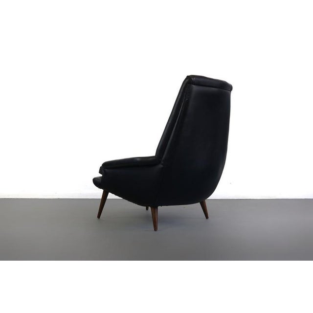 An exquisite architectural design in it's original black vinyl upholstery w/ tufted button back detailing set on tapered...