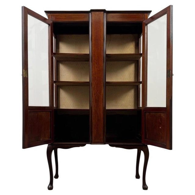 An elegant early 20th-century English display cabinet, finely crafted from mahogany and distinguished by delicate...