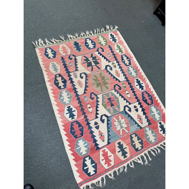 Design Plus Gallery presents a 3ft 7in × 5ft Handwoven Kilim Rug. This flatweave rug displays a coral-red field with...