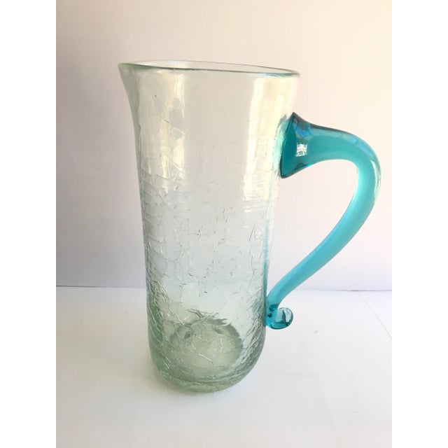 An unusual pitcher in that it is clear glass with a sightly green hue especially at the bottom. Artfully constructed using...