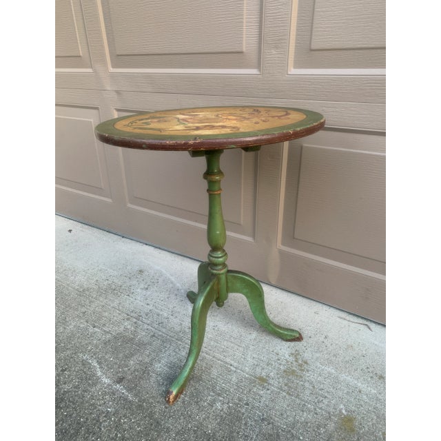 An elegant Regency-style flip-top side table in painted walnut, featuring hand-painted decoration against a green ground....