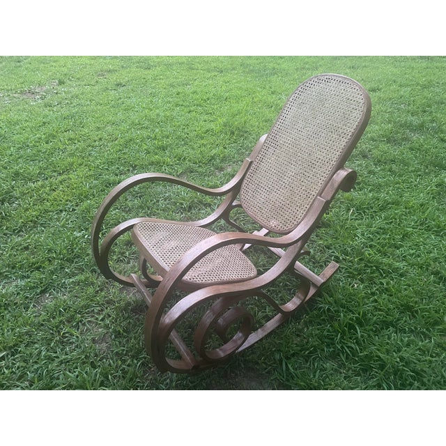 Beautiful vintage bentwood rocking chair featuring an elegant steam-bent wood frame with hand-caned seat and oval...