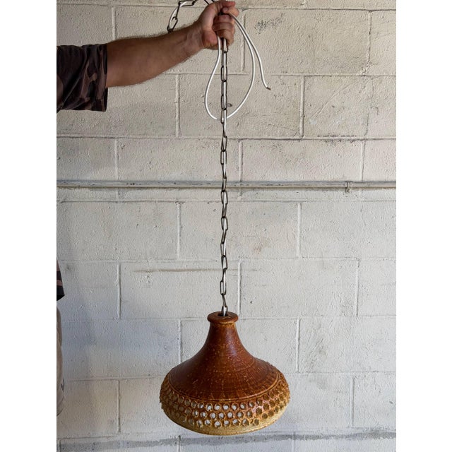 This charming pendant lamp features a textured ceramic shade and hanging chain. The warm silhouette brings cozy...