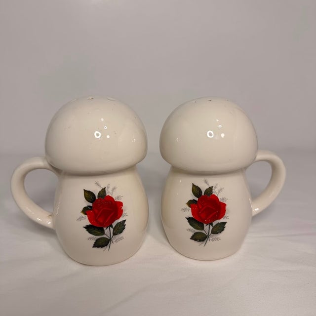 This product is a set of two vintage 1970s salt and pepper shakers with rose and mushroom handles in white ceramic. The...