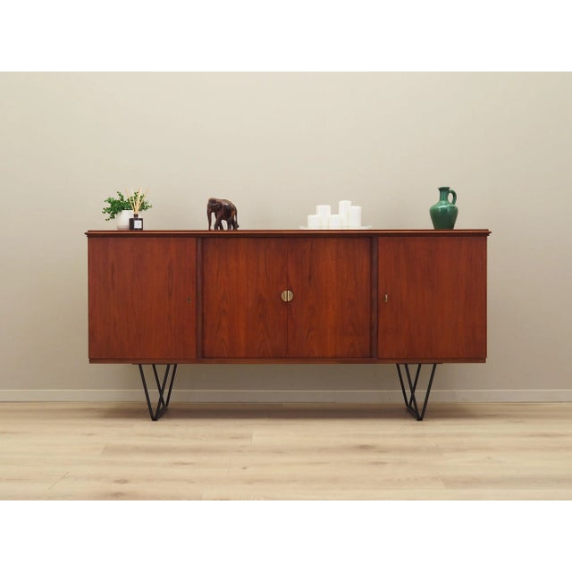 The sideboard was made in the 1970s, Danish production. The structure is covered with teak veneer. Legs made of metal...