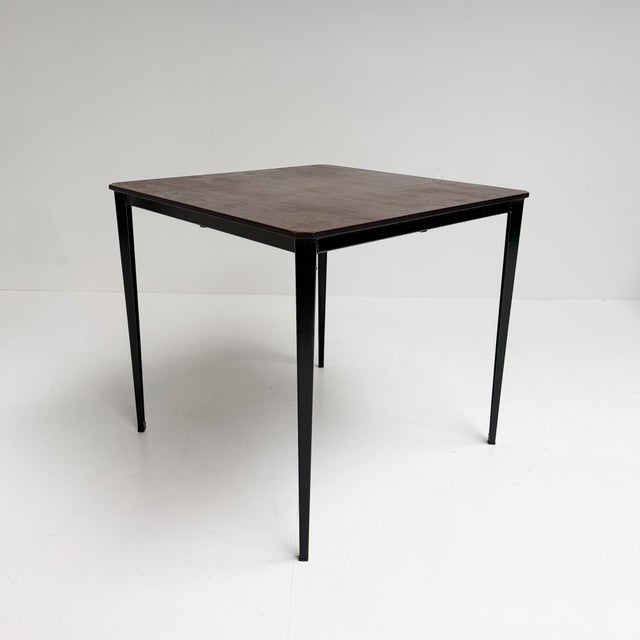 This square vintage dining table by Wim Rietveld combines sleek industrial styling with the warm appeal of wood. Dating...