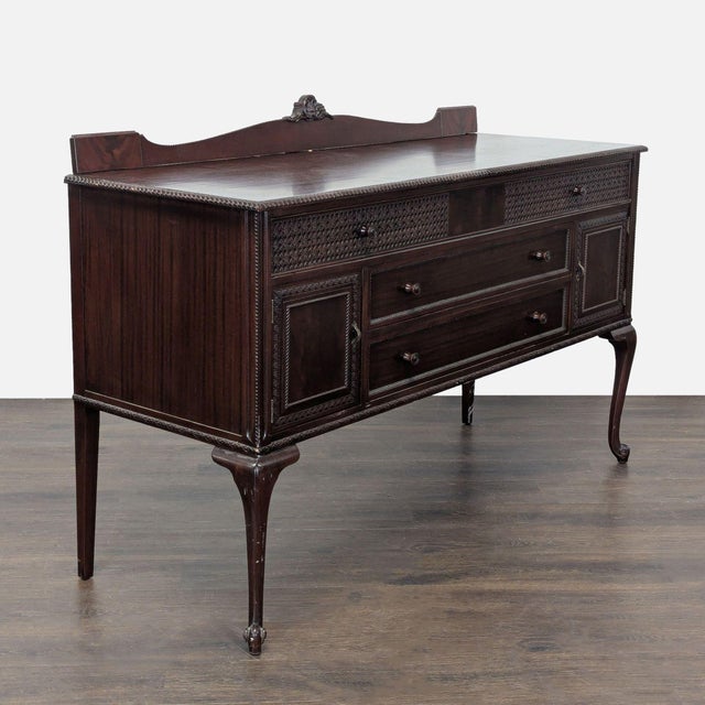 Solid wood carved sideboard with 3 drawers and 2 cabinets. One of the drawers has divided sections for utensils. Brand:...
