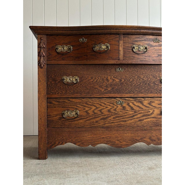 Antique chest of drawers with a softly bowed serpentine front and pronounced cathedral-grain oak. Two-over-two drawer...