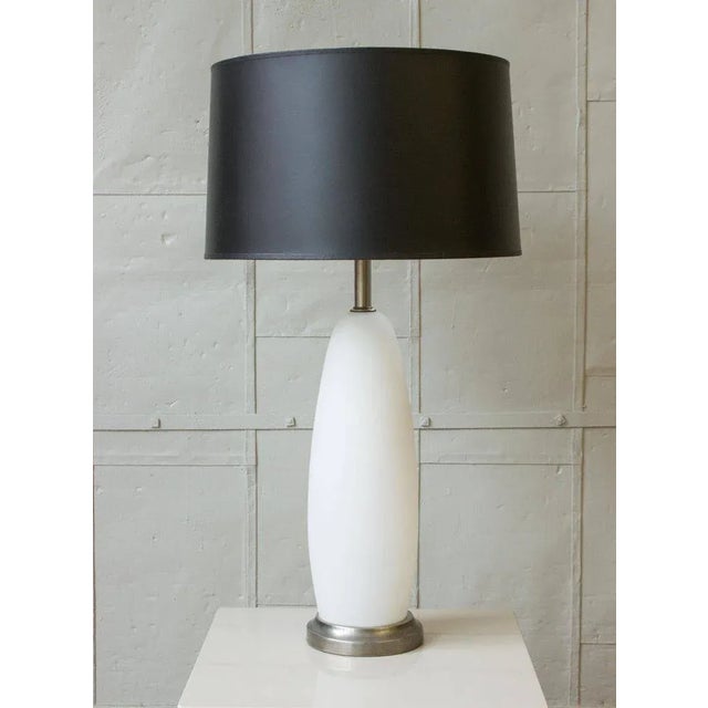 An elegant pair of Italian Mid-Century Murano glass table lamps featuring frosted white glass bodies accented by antique...