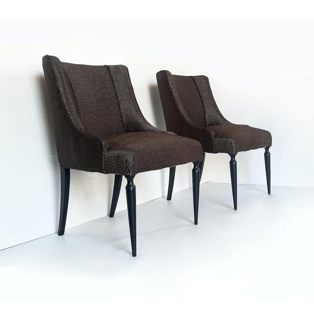 Particular pair of 50s armchairs entirely in brown fabric and characterized by mahogany wooden legs and small brass...