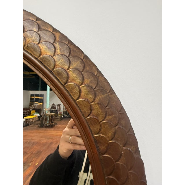 A dramatic and sculptural round wall mirror of exceptional decorative presence, featuring a deeply molded giltwood frame...