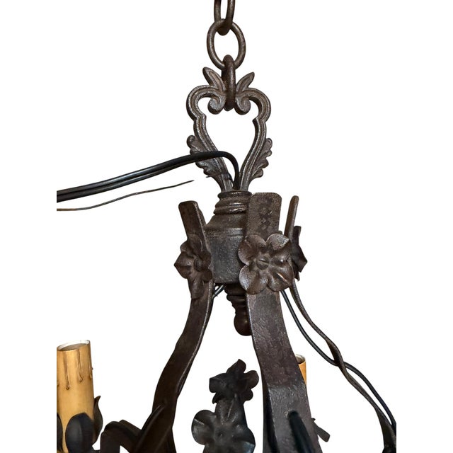 This antique French chandelier features six ornate wrought iron arms with floral details. It showcases candelabra-style...