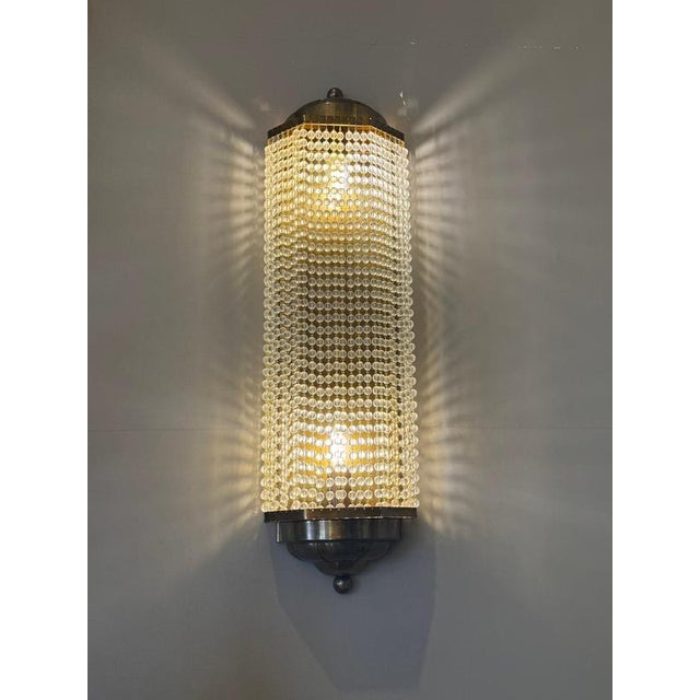 A striking set of four Art Deco wall sconces featuring cylindrical curtains of finely strung crystal beads framed by warm...