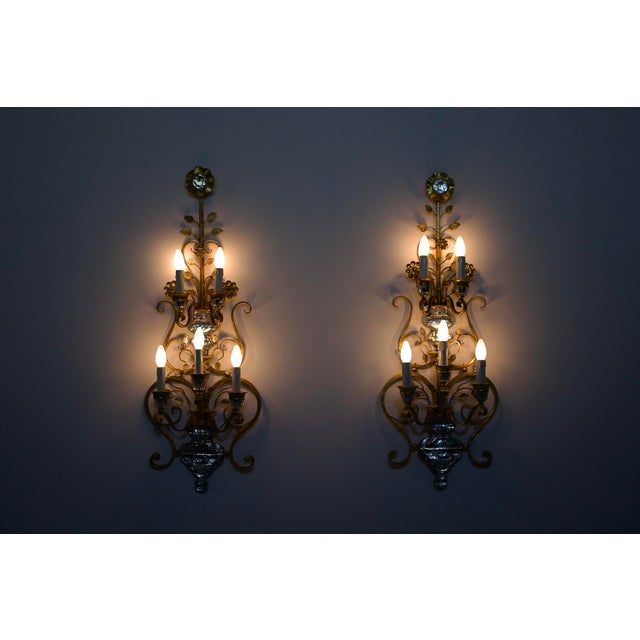 Two imposing pairs of crystal and gilt wrought iron wall lights, giovanni banci, italy, 1970s. Each light fixture is...