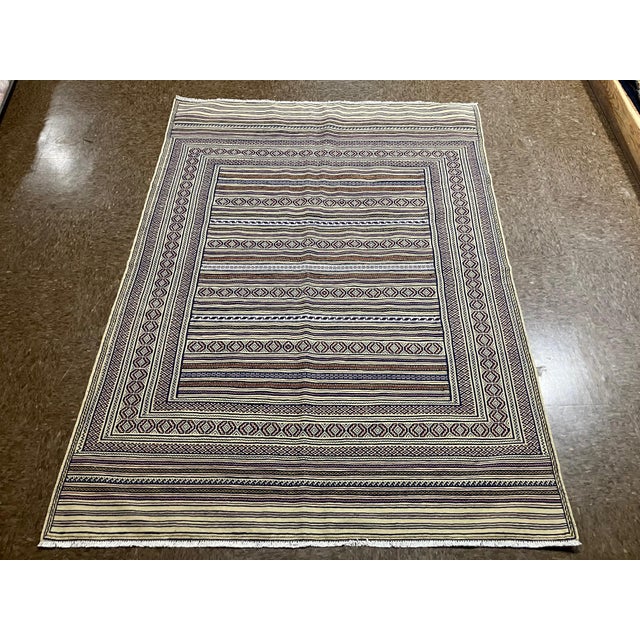 Handwoven Persian kilim flatweave rug featuring a striped field with alternating bands of geometric and linear motifs. The...