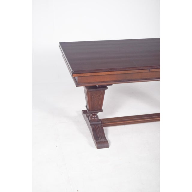 Rectangular extendable dining table. The top has straight edges with a stepped profile, showing a geometric design...
