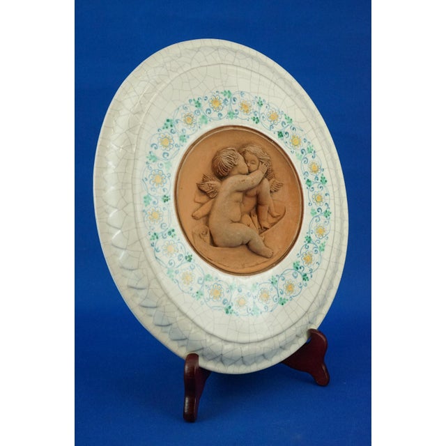 A delightful ellipsoidal majolica plaque, entirely hand-decorated with brush-tipped floral decorations surrounding a...