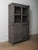 A grounded, architectural form rendered in a deep charcoal wash, this cabinet balances transparency and solidity through...