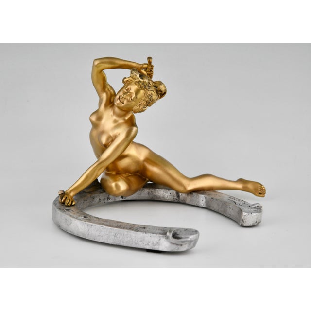 This exceptional Art Nouveau bronze sculpture by Georges Récipon depicts a nude female figure reclining on a horseshoe....