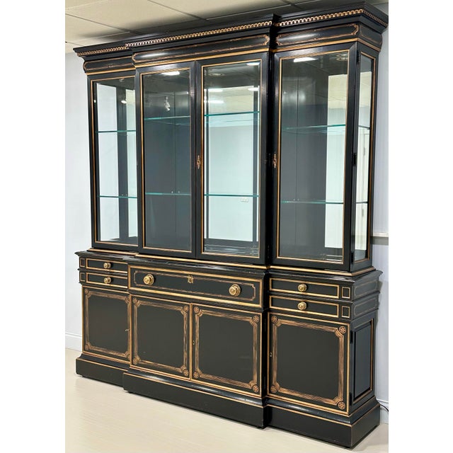 A striking black and gilt lacquered breakfront display cabinet by Karges Furniture, executed in a refined Neoclassical /...