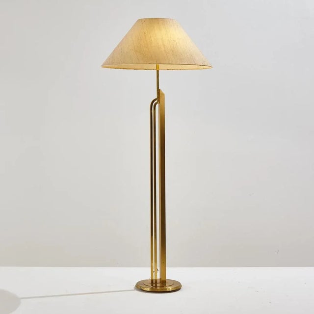 Floor lamp with triple brass stem. With stains on the textile lampshade and surface scratches on the metal parts. The...