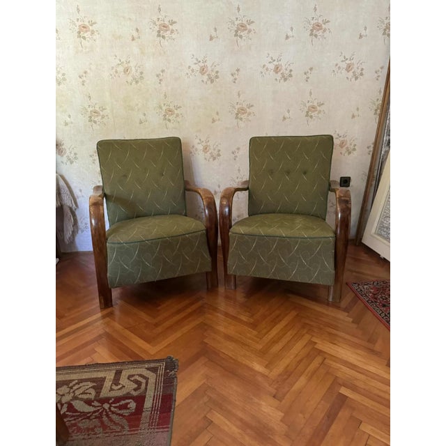 Elegant pair of 1930s Art Deco lounge chairs featuring beautifully curved wooden armrests and a classic silhouette. These...
