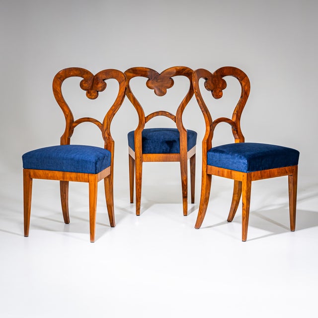 Biedermeier side chairs veneered in walnut, featuring heart-shaped backs with an openwork trefoil motif. The chairs have...