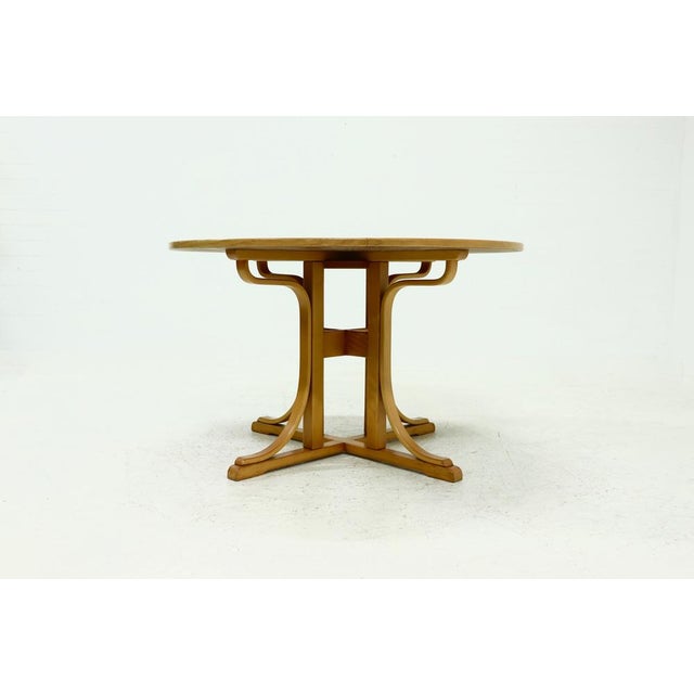 Round dining table from the 1980s. The table is defined by its architectural and sculptural base, where curved wooden...