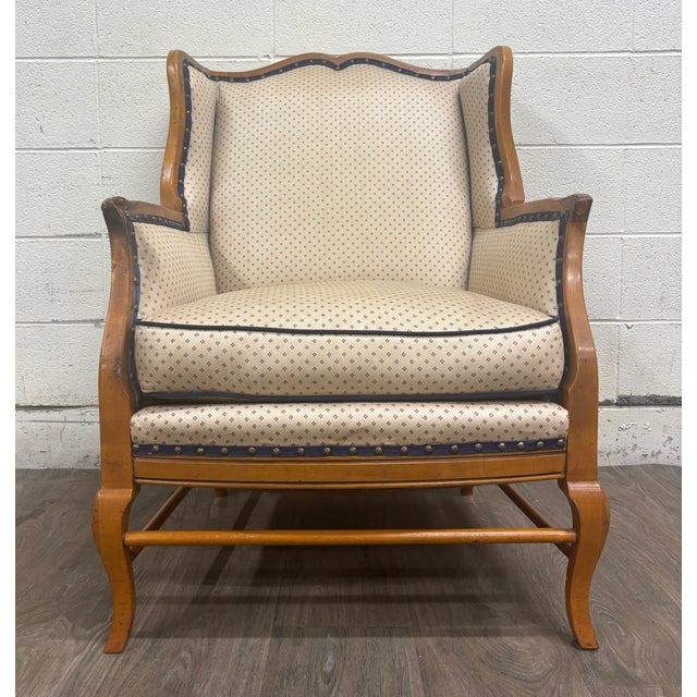 This is a vintage Country French wingback chair possibly attributed to Baker Furniture, featuring a warm fruitwood frame,...