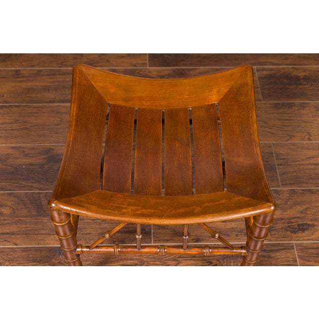An English Egyptian Revival walnut Thebes stool from the early 20th century, with slatted curving seat and faux bamboo...