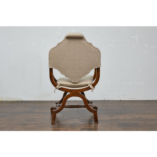 An Italian walnut Curule armchair from the 19th century with upholstered seat and back and X-Form carved base. This...